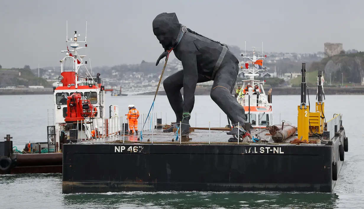 Patung perunggu terbesar di Inggris,  berjudul 'Messenger' tiba dengan tongkang di pesisir pantai Plymouth, Senin (18/3). Nantinya patung dengan tingggi 7 meter itu bakal dipajang di depan gedung teater kota, Theatre Royal. (REUTERS/Peter Nicholls)