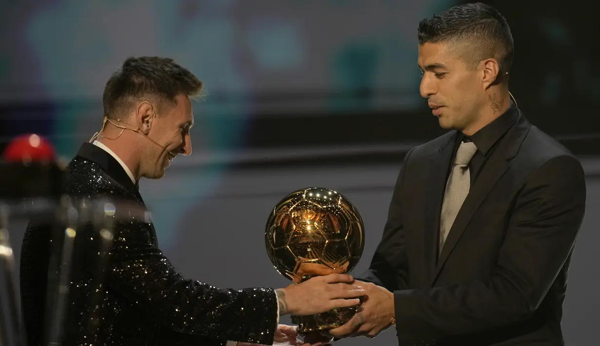 Striker PSG, Lionel Messi menerima trofi Ballon d'Or 2021 dari mantan rekan setimnya di Barcelona Luis Suarez pada acara penganugerahan di Theatre du Chatelet, Paris, Prancis, Senin (29/112021). Lionel Messi menjadi kolektor Ballon d'Or terbanyak dengan total raihan tujuh trofi. (AP Photo/Christophe