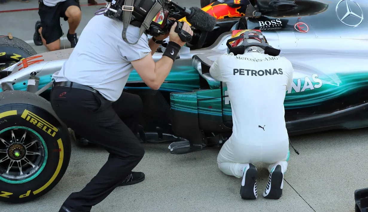 Lewis Hamilton merayakan kemenangannya bersama mobil yang dikendarainya pada GP F1 Jepang di Sirkuit Suzuka, Jepang, (8/10). Dengan kemenangan ini, Hamilton menjauh dari Sebastian Vettel di klasemen F1. (AP Photo / Eugene Hoshiko)