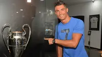 Cristiano Ronaldo menunjuk replika Piala Champions di Museum CR7 di Funchal, Madeira, Portugal (23/7). Museum tersebut berisi perjalanan karier Ronaldo selama bertahun-tahun menggeluti dunia lapangan hijau. (AFP PHOTO/Helder Santos)