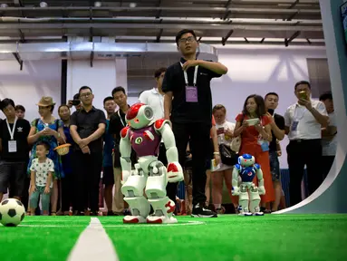 Pengunjung menyaksikan pertandingan sepak bola yang dimainkan oleh robot dari perusahaan teknologi Softbank pada Konferensi Robot Dunia di Beijing, China, Rabu (15/8). (AP Photo/Mark Schiefelbein)