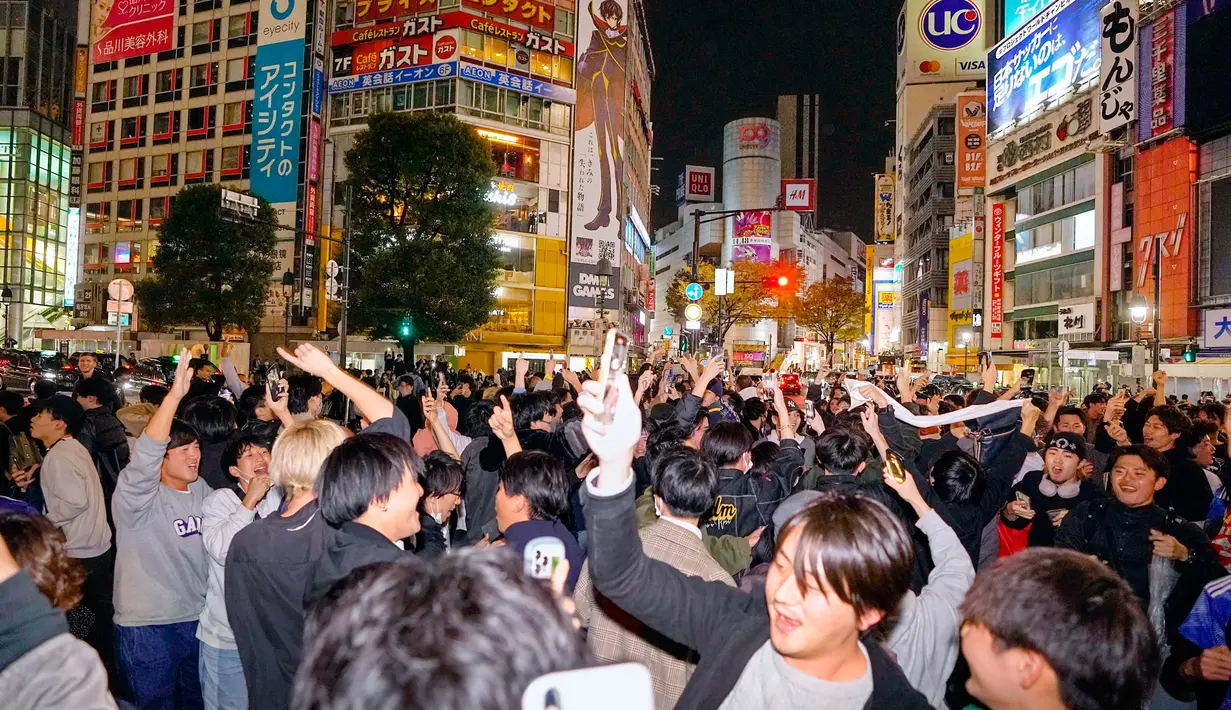 Orang-orang merayakan kemenangan timnas Jepang saat melawan Jerman di Piala Dunia Qatar 2022 di persimpangan Shibuya, Tokyo, Jepang, Kamis (24/11/2022). Jepang mencetak dua gol pada babak kedua dalam pertandingan yang dilakukan di Stadion Internasional Khalifa, Doha. (Kyodo News via AP)