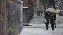 Dua wanita berjalan saat salju turun di Madrid, Spanyol, Jumat (8/1/2021). Badai Filomena mengakibatkan salju lebat turun di Madrid dan seluruh Spanyol. (PIERRE-PHILIPPE MARCOU/AFP)