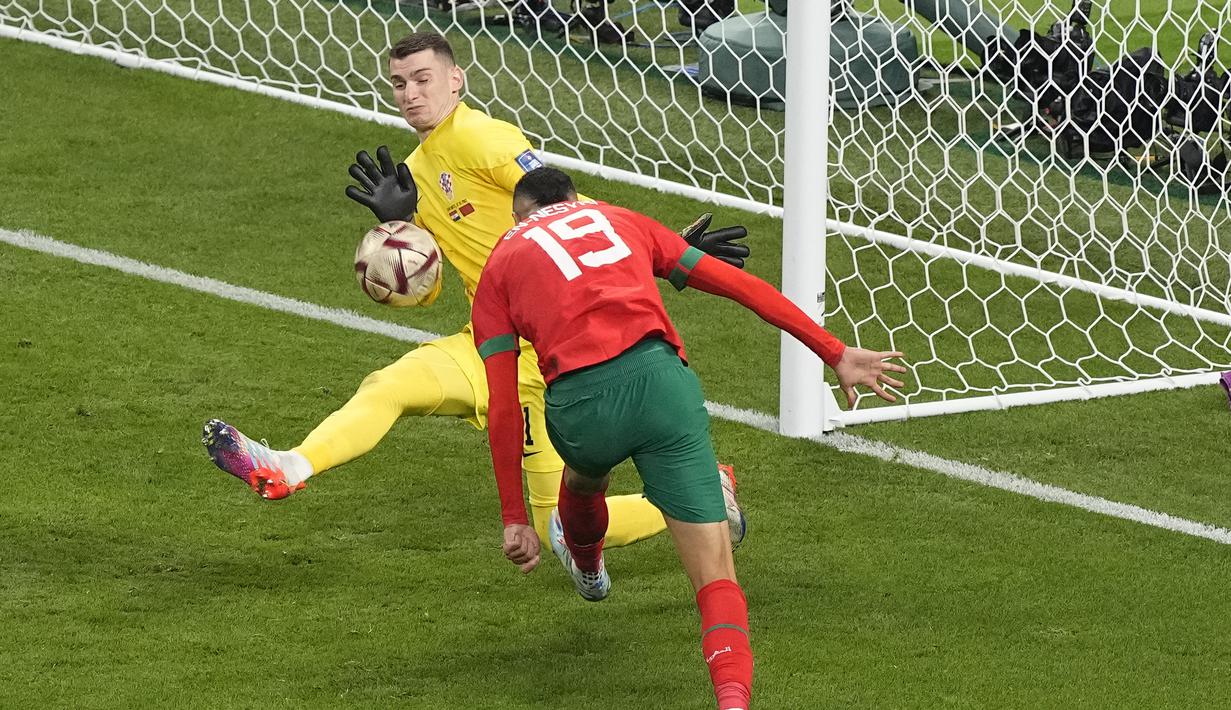 Penyerang Maroko, Youssef En-Nesyri berusaha mencetak gol ke gawang kiper Kroasia,  Dominik Livakovic selama pertandingan playoff perebutan peringkat ketiga Piala Dunia 2022 di Khalifa International Stadium di Doha, Qatar, Sabtu (17/12/2022). Kroasia meraih juara ketiga Piala Dunia 2022 usai menang 2-1 atas Maroko. (AP Photo/Martin Meissner)