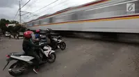 Pengendara sepeda motor menghentikan kendaraannya saat sebuah kereta api melintas di perlintasan kereta api tanpa palang pintu di kawasan Kelingkit, Rawa Buaya, Jakarta Barat, Selasa (26/2). (Liputan6.com/Johan Tallo)