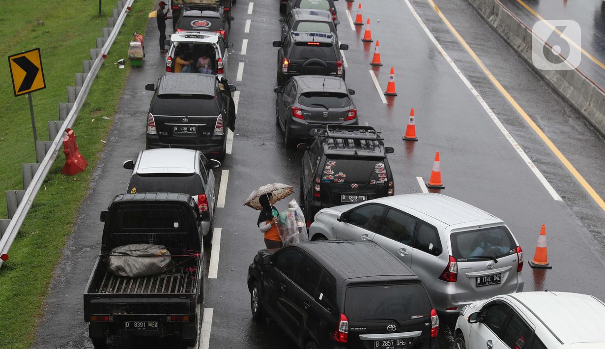 Seorang pedagang asongan menawarkan dagangan kepada pengendara di jalan tol Jagorawi yang sedang menanti waktu buka tutup jalur menuju kawasan wisata puncak, Bogor, Jawa Barat, Sabtu (31/10/2020). (Liputan6.com/Helmi Fithriansyah)