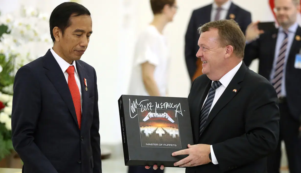 Perdana Menteri Denmark Lars Lokke Rasmussen memberikan Presiden Joko Widodo (Jokowi) cendera mata piringan hitam band Metallica usai pernyataan bersama dalam kunjungan kerja PM Denmark di Istana Bogor, Jawa Barat, Selasa (28/11). (AP/Dita Alangkara)