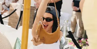 Model Kendall Jenner, tampil dengan tas Duo Mini Kate Spade New York berwarna Garden Soil, lengkap dengan Bag Charm Dog Dangle dari Kate Spade New York. (Foto: Kate Spade.dok)