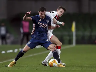 Bek Arsenal, Cedric Soares berebut bola dengan penyerang Dundalk, Jamie Wynne dalam pertandingan Grup B Liga Europa 2020/2021 di Stadion Aviva, Jumat (11/12/2020) dini hari WIB. Arsenal menang 4-2 saat bertandang di markas wakil Irlandia, Dundalk. (Brian Lawless/PA via AP)