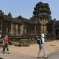 Sejumlah wisatawan berjalan di Candi Angkor Wat, Provinsi Siem Reap, Kamboja, Kamis (5/3/2020). Menurut World Travel and Tourism Council, wabah virus corona (COVID-19) membuat sektor pariwisata dunia kehilangan USD 22 miliar. (TANG CHHIN Sothy/AFP)