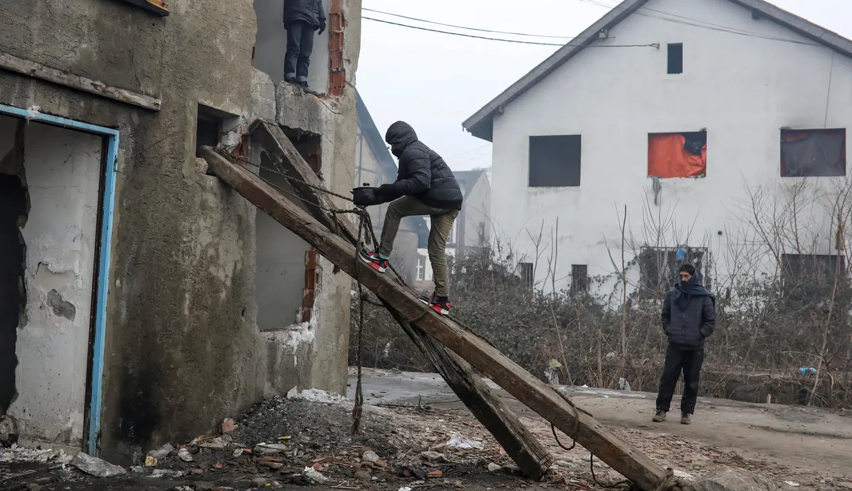 Seorang imigran membawa makanan ke sebuah gudang tak terpakai di Belgrade, Serbia, Kamis (22/12). (REUTERS / Marko Djurica)