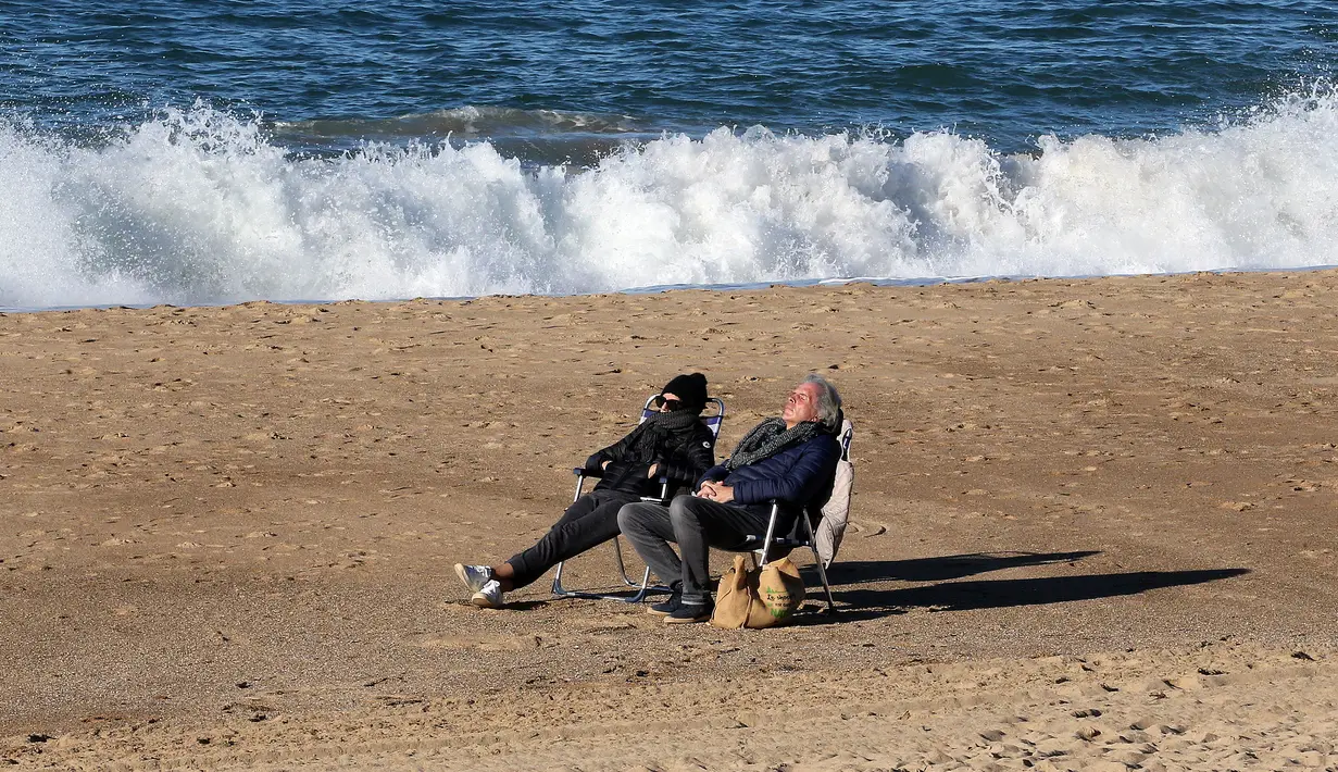 Orang-orang berjemur di pantai di Saint-Jean-de-Luz barat daya Prancis, Rabu (2/2/2022). Inggris, Prancis, Irlandia, Belanda, dan beberapa negara Nordik telah mengambil langkah-langkah untuk mengakhiri atau melonggarkan pembatasan covid-19 mereka. (AP Photo/Bob Edme)