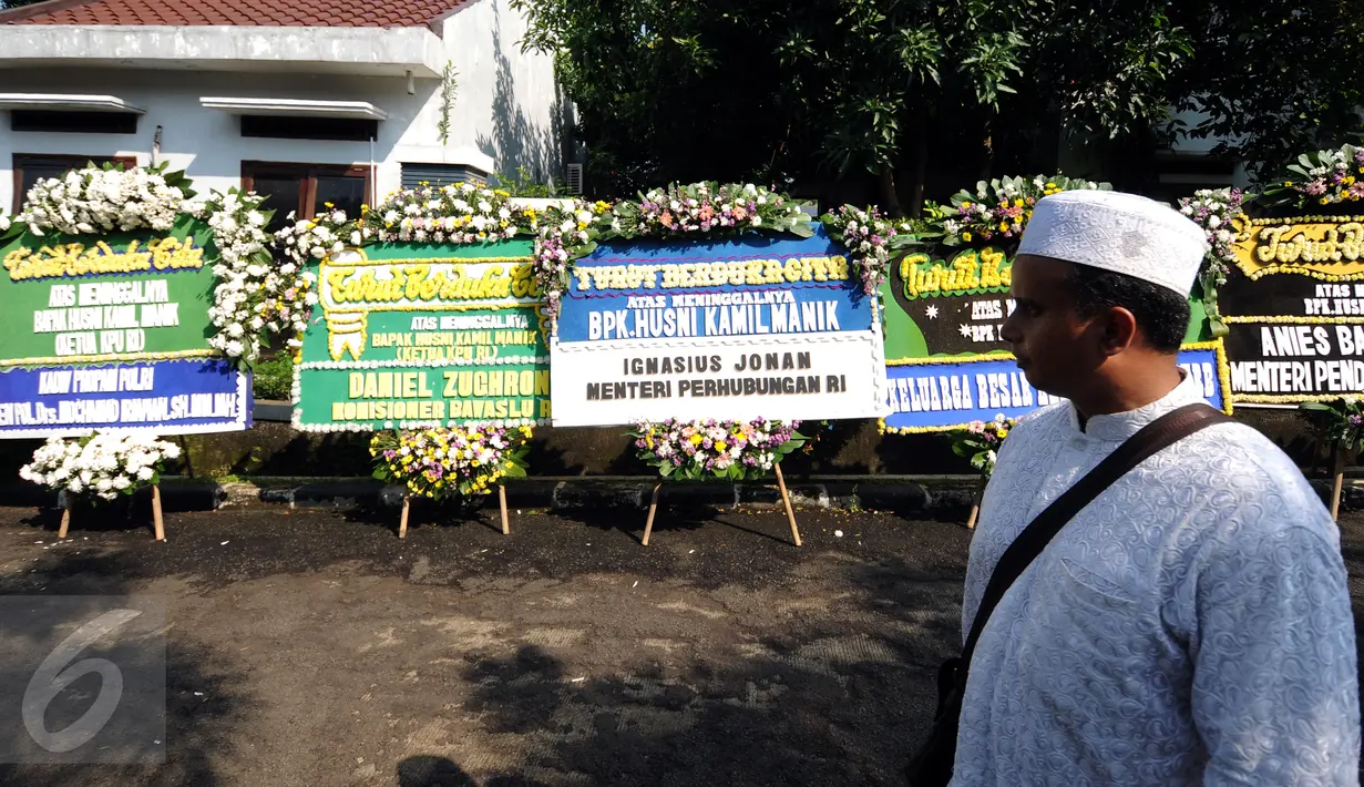 Pelayat melintasi karangan bunga duka cita wafatnya Ketua KPU Husni Kamil Manik di Kompleks KPU, Jakarta, Jumat (8/7). Sejumlah pejabat tinggi negara hadir melayat jenazah Husni Kamil Manik yang wafat, Kamis (7/7). (Liputan6.com/Helmi Fithriansyah)