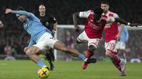 Pemain Manchester City, Jack Grealish (kiri) berebut bola dengan pemain Arsenal, Bukayo Saka pada laga pekan ke-23 Liga Inggris 2022/2023 yang berlangsung di Emirates Stadium, London, Kamis (16/02/2023) WIB. The Cityzens berhasil menang dengan skor 3-1. (AP Photo/Kin Cheung)