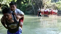 Siswa SD peserta Ujian Sekolah Berstandar Nasional, korban banjir bandang di Pameungpeuk, Garut, Jabar, Selasa (10/5) melintasi Sungai Ciawi karena jembatan ambruk diterjang banjir. (Antara)