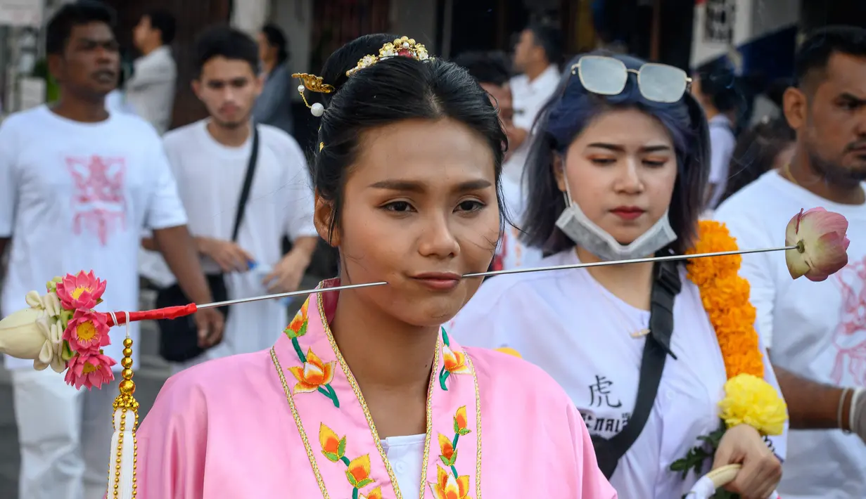 Seorang wanita menusuk pipinya dengan besi  saat mengikuti prosesi perayaan Festival Vegetarian tahunan di Phuket, Thailand, Kamis (3/10/2019). Festival dimulai pada malam pertama bulan lunar kesembilan dan berlangsung selama sembilan hari. (AFP Photo/Mladen Antonov)