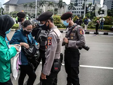 Polisi memeriksa barang bawaan mahasiswa yang akan berunjuk rasa di Patung Kuda, Jakarta, Selasa (20/10/2020). Pemeriksaan tersebut dilakukan untuk memastikan unjuk rasa berjalan aman dan damai. (Liputan6.com/Faizal Fanani)