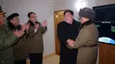 Pemimpin Korea Utara Kim Jong Un tertawa bersama sejumlah orang berseragam militer saat rudal balistik antar benua berhasil diluncurkan di di sebuah ruangan di Korea Utara (29/11). (KCNA/Korea News Service via AP)