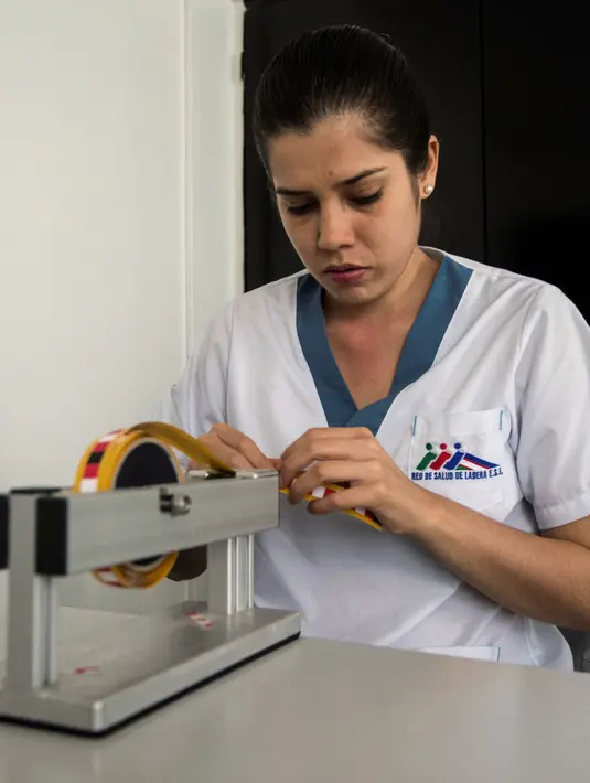 Petugas medis, Leidy Garcia menyiapkan potongan pita dengan koordinat Braille untuk pemeriksaan payudara di sebuah rumah sakit di Cali, Kolombia (14/11). Leidy Garcia dan Francia Papamija bekerja sebagai Medical Tactile Examiners. (AFP/Luis Robayo)