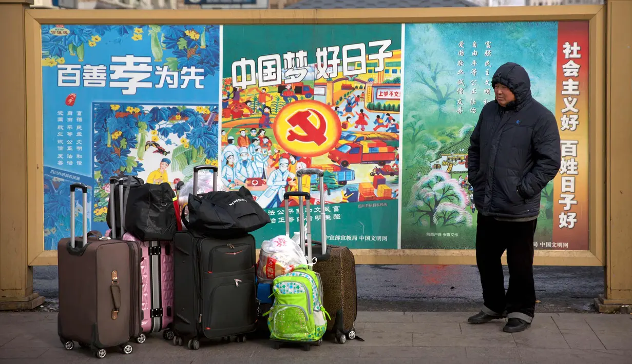 Seorang pria berdiri di samping barang bawaannya di Stasiun Kereta Api Beijing, (9/2). Sambut perayaan Imlek 2018, Jutaan warga China mulai memenuhi stasiun, bandara dan jalan yang diperkirakan akan dimulai akhir pekan ini. (AP Photo/Mark Schiefelbein)