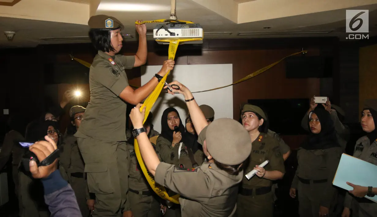 Petugas Satpol PP wanita memasang garis polisi Pamong Praja di Sense Karaoke di Mangga Dua Square, Jakarta, Kamis (19/4). Pemprov DKI Jakarta menutup Sense Karaoke setelah adanya penggerebekan dan penggeledahan di lokasi. (Liputan6.com/Arya Manggala)