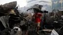 Seorang warga mengangkat puing-puing bangunan usai kebakaran kota Quezon, Metro Manila di Filipina (28/12). Dalam kejadian ini sejumlah warga mengalami luka-luka dan tidak ada korban jiwa. (REUTERS/Erik De Castro)