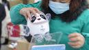 Seorang karyawan mengemas boneka mainan maskot Olimpiade Musim Dingin Beijing 2022 Bing Dwen Dwen di sebuah pabrik di Nantong di provinsi Jiangsu Timur, China (8/2/2022). (AFP Photo/STR)
