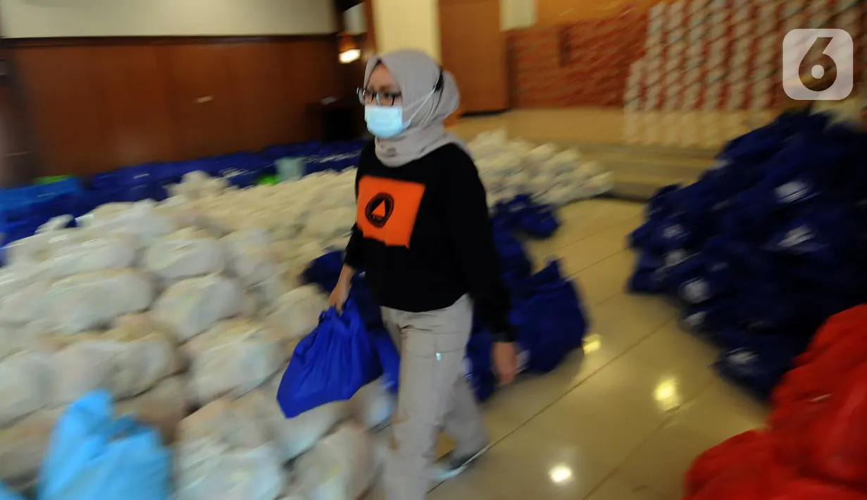 Seorang wanita membawa bansos berupa bahan pangan untuk didistribusikan kepada warga terpapar COVID-19 yang menjalani isolasi mandiri di rumah di Gedung Wanita, Kota Bogor, Jumat (9/7/2021). Bansos ini sumbangan instansi pemerintah dan swasta, pegawai negeri dan perorangan. (merdeka.com/Arie Basuki)