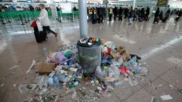 Penumpang berjalan melewati sampah yang berserakan di Bandara Barcelona, Spanyol, Kamis (1/12). Sampah-sampah yang berserakan tersebut sebagai bentuk aksi protes para petugas kebersihan untuk pemotongan anggaran 1,3 juta Euro. (REUTERS/Albert Gea)