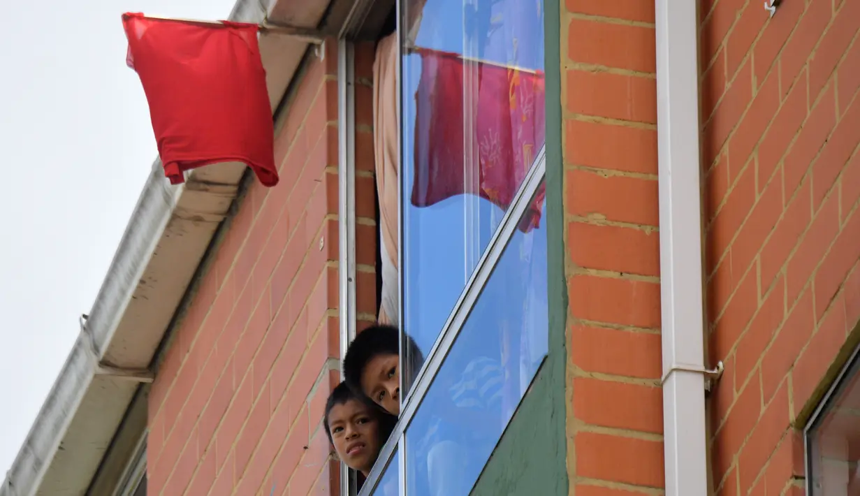 Orang-orang menggantungkan kain merah di rumah mereka untuk meminta bantuan makanan selama lockdown di kotamadya Soacha, dekat Bogota, 4 April 2020. Presiden Kolombia Ivan Duque menetapkan lockdown dari 24 Maret hingga 13 April sebagai langkah mencegah penyebaran virus corona. (Raul ARBOLEDA/AFP)