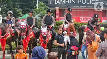 Sejumlah warga dan anak-anak berfoto dengan Polisi Berkuda dari Detasemen Turangga Direktorat Polisi Satwa Polri saat Car Free Day (CFD) atau Hari Bebas Kendaraan Bermotor di kawasan Bundaran HI, Jakarta, Minggu (19/2/2023).Polisi berkuda selain ditugaskan untuk pengamanan simpatik juga untuk menghibur warga dan anak-anak saat Hari Bebas Kendaraan Bermotor serta memperkenalkan profesi tersebut kepada warga. (Lipitan6.com/Angga Yuniar)