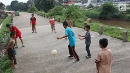 Anak-anak bermain sepak bola di jalur inspeksi Sungai Ciliwung di kawasan Rawajati, Jakarta, Rabu (23/1). Keterbatasan lahan tidak menyurutkan semangat mereka untuk bermain sepak bola meski di tempat seadanya. (Liputan6.com/Immanuel Antonius)