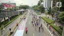 Suasana saat sejumlah orang yang mengenakan batik berjalan di catwalk sepanjang Jalan Jenderal Sudirman, Jakarta, Minggu (2/10/2022). Kegiatan yang diikuti ratusan orang ini diselenggarakan oleh Bank Mandiri untuk menyambut Hari Batik Nasional yang jatuh setiap tanggal 2 Oktober 2022. (Liputan6.com/Faizal Fanani)