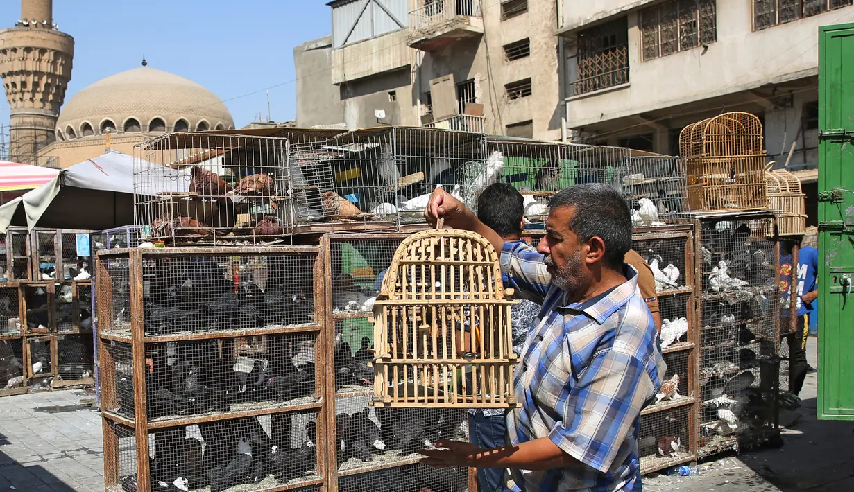 Seorang pria Irak membawa burung di dalam sangkar burung di pasar hewan peliharaan al-Ghazal di ibukota Irak, Baghdad (11/10/2019). Pasar hewan peliharaan yang berada di kota Baghdad ini telah ada sejak tahun 1950-an. (AFP Photo/Ahmad Al-Rubaye)