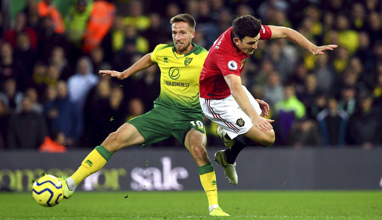 Bek Manchester United, Harry Maguire, terjatuh saat berebut bola dengan pemain Norwich City, Marco Stiepermann, pada laga Premier League 2019 Stadion Carrow Road, Norwich, Minggu (27/10). Manchester United menang 3-1 atas Norwich City. (AP/Joe Gidden)