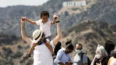 Pengunjung mengenakan masker di luar ruangan saat mengambil gambar tanda Hollywood di Observatorium Griffith di Los Angeles, Senin (17/5/2021). California mempertahankan aturan mengenakan masker hingga negara bagian itu mencabut pembatasan COVID-19 pada 15 Juni. (AP Photo/Damian Dovarganes)