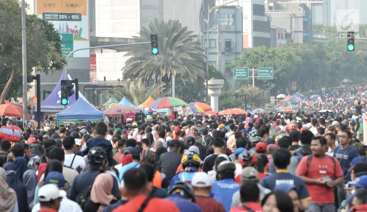 Sejumlah payung milik PKL terlihat di antara kerumunan warga selama car free day di kawasan MH Thamrin, Jakarta, Minggu (8/9/2019). Penutupan sebagian jalan akibat proyek revitalisasi trotoar membuat para PKL menggelar lapak hingga ke badan jalan. (merdeka.com/Iqbal S. Nugroho)