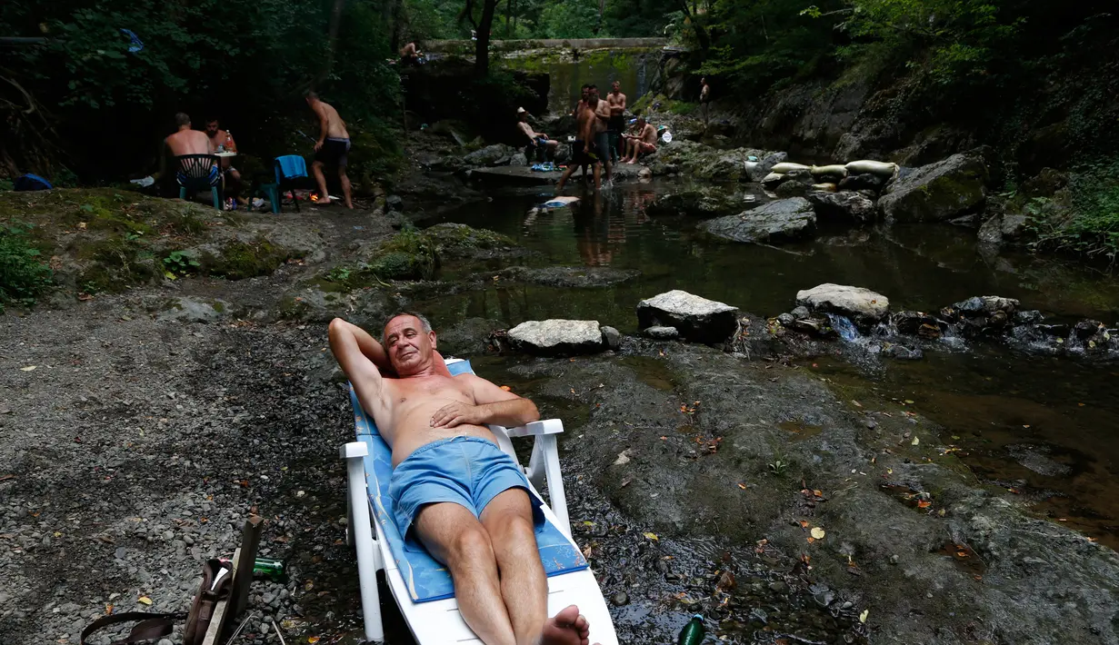 Pria Bosnia beristirahat di dekat sebuah sungai kecil berlindung dari tempat yang sangat panas, dekat Tuzla, Bosnia, 6 Agustus 2017. Cuaca panas telah melanda Bosnia dengan suhu hingga 40 celcius di sebagian besar wilayah. (AP Photo / Amel Emric)