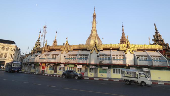 Kendaraan melewati Pagoda Sule di Yangon saat militer Myanmar merebut kekuasaan pemerintah, Senin (1/2/2021). Rekaman video yang disiarkan di televisi milik militer mengatakan kekuasaan telah diserahkan kepada panglima tertinggi militer Myanmar, Jenderal Senior Min Aung Hlaing. (AP Photo/Thein Zaw)