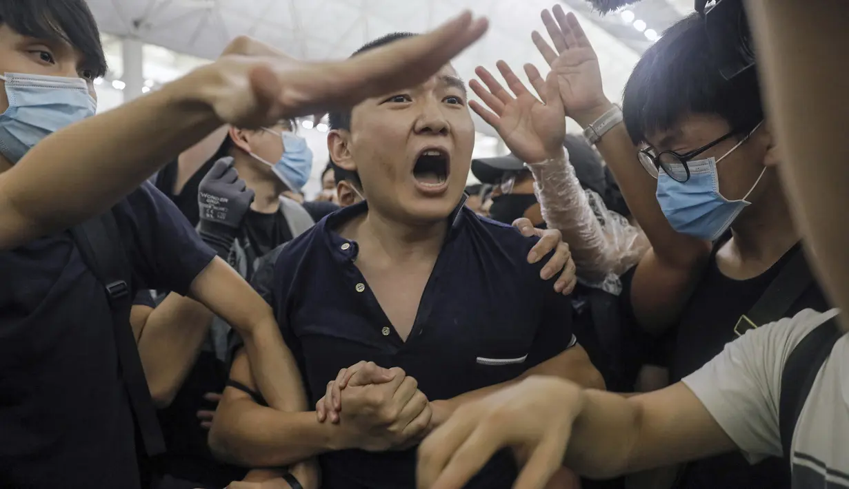 Seorang pria yang diduga mata-mata China berteriak saat diikat oleh pemrotes pro-demokrasi saat unjuk rasa di bandara internasional Hong Kong (13/8/2019). Pria ini jadi bulan-bulanan demonstran saat unjuk rasa di bandara Hong Kong. (AP Photo/Vincent Yu)
