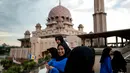 Gambar pada 22 November 2017, anak-anak sekolah berfoto dengan latar belakang masjid berwarna pink di kawasan Putrajaya, Malaysia. Karena keunikannya, masjid ini memiliki fungsi ganda sebagai rumah ibadah dan juga objek wisata. (MANAN VATSYAYANA/AFP)