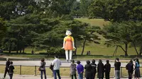 Pengunjung melihat boneka 'Younghee' yang menjadi maskot dalam serial Netflix asal Korea, Squid Game, di Olympic park, Seoul, Selasa (26/10/2021). Boneka setinggi empat meter atau 13 kaki itu, akan dipamerkan di taman tersebut selama tiga bulan. (AP Photo/Lee Jin-man)