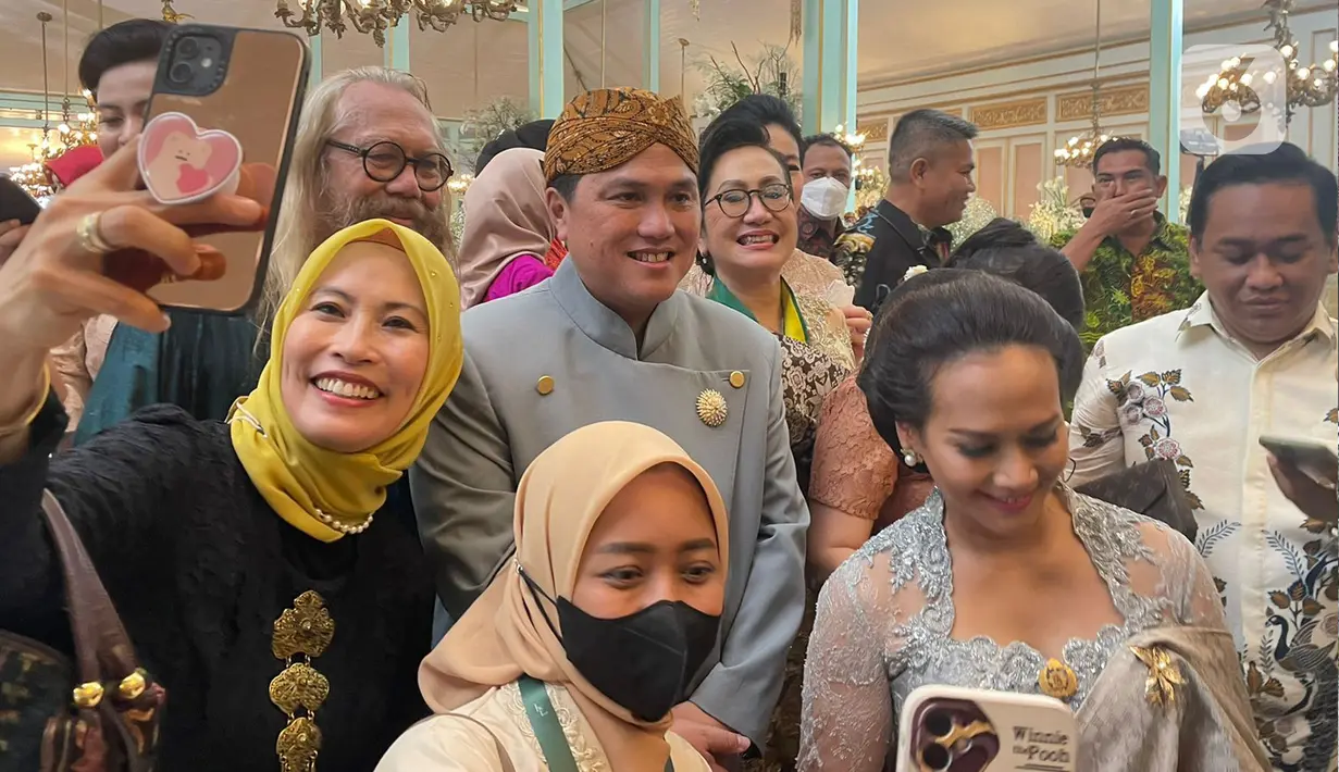 Sejumlah warga berfoto dengan Menteri BUMN Erick Thohir pada acara Ngunduh Mantu pernikahan putra bungsu Presiden Joko Widodo, Kaesang Pangarep dan istrinya Erina Gudono di Pura Mangkunegaran, Solo, Minggu (11/12/2022). (Liputan6.com/Herman Zakharia)