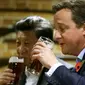 Perdana Menteri Inggris David Cameron (kanan) minum bir bersama Presiden China Xi Jinping di sebuah bar, Inggris, (22/10/2015). Di sela kunjungan ke Inggris, Presiden Cina Xi Jinping diajak PM David Cameron untuk minum bir. (REUTERS/Kirsty Wigglesworth)