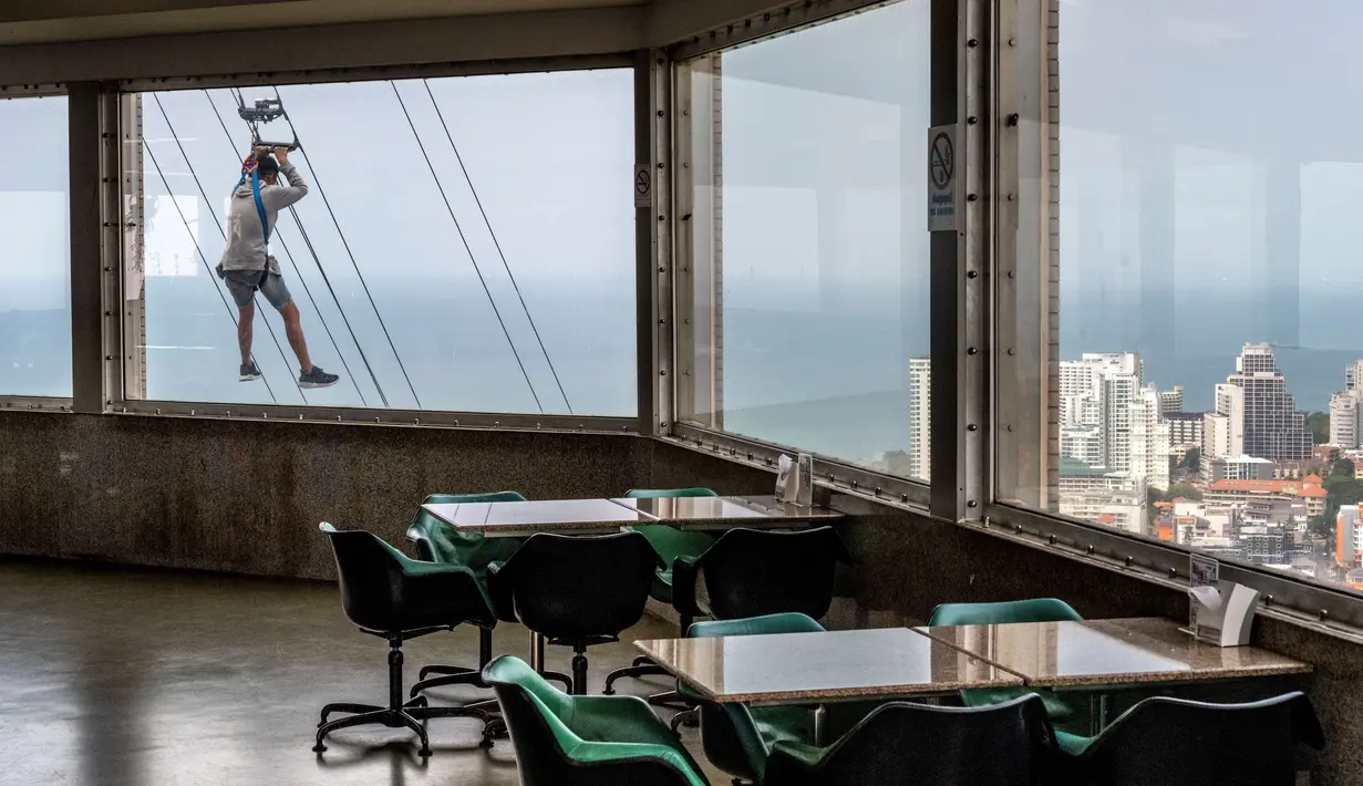 Seorang turis menaiki zipline dari lantai 55 menara observasi Park Beach Resort di Pattaya, Thailand, Rabu (12/2/2020). Pattaya Park Beach Resort adalah salah satu primadona bagi wisatawan China di Pattaya  yang kini berangsur sepi karena penyebaran virus corona covid-19. (Mladen ANTONOV / AFP)