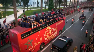 Para pemain timnas Maroko melakukan selebrasi di atas bus dan melambaikan tangan ke publik saat parade di Rabat , Maroko, 20 Desember 2022. Timnas Maroko mendapat sambutan hangat di negaranya setelah berhasil meraih juara keempat Piala Dunia 2022. (AP Photo/Mosa'ab Elshamy)