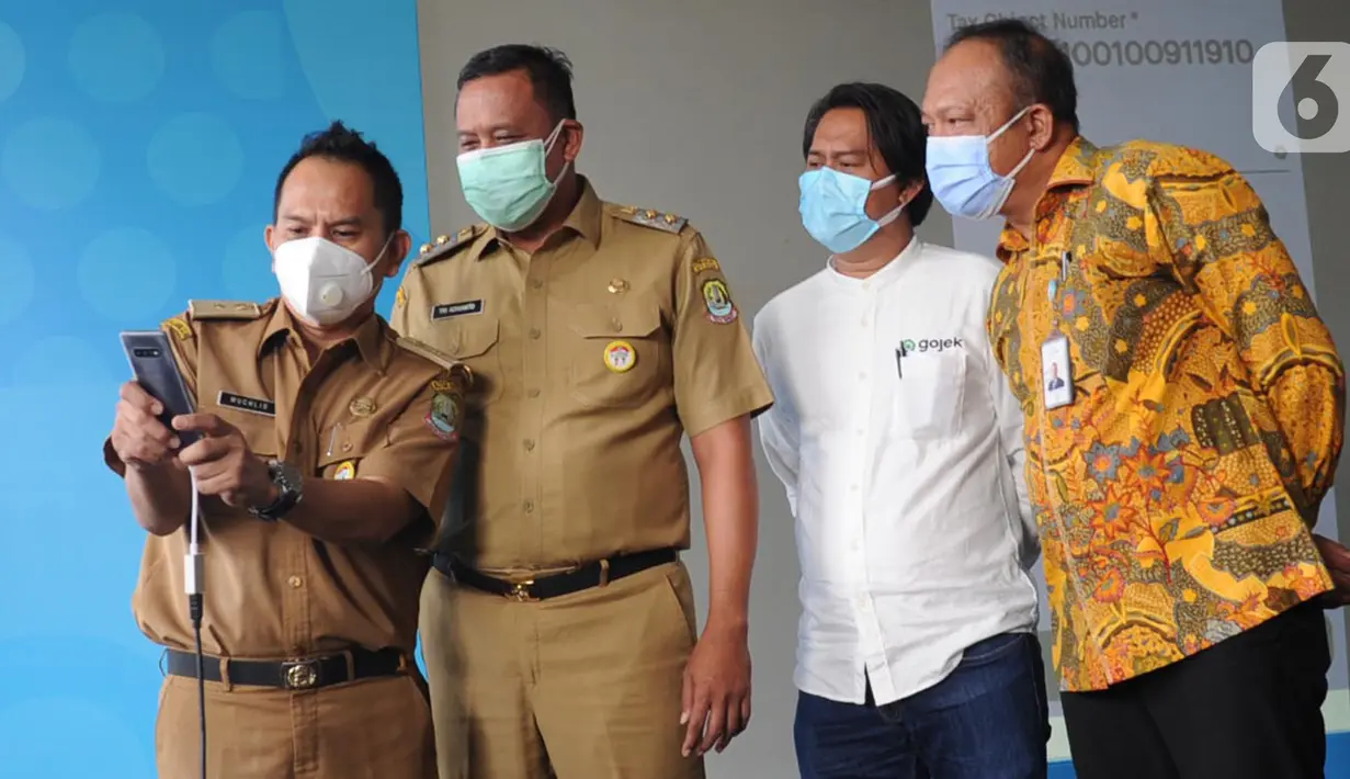 Perwakilan Bapenda Kota Bekasi Muchlis, Wakil Walikota Tri Adhianto, VP Regional Operations Gojek Jabodetabek Gede Manggala dan Pimpinan Bank BJB Cabang Bekasi Adie Arief Wibawa mencoba pembayaran PBB non-tunai melalui GoTagihan di aplikasi Gojek, Bekasi, Senin (14/12/2020). (Liputan6.com/HO/Ading)