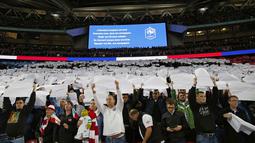 Suporter Inggris mengangkat kertas putih, yang merupakan bagian dari bendera Prancis pada laga Persahabatan antara Prancis vs Inggris di Stadion Wembley, London, Rabu(18/11/2015) dini hari WIB.  (AFP Photo/Ian Kington)