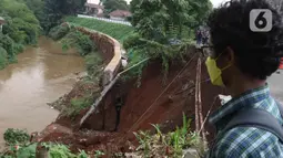 Warga melihat Lokasi longsor di daerah bantaran sungai Ciliwung, Pengadegan Timur, Jakarta, Selasa (12/4/2022). Longsor sepanjang 25 meter, lebar lima meter, dan kedalaman 15 meter itu menyebabkan 4 sepeda motor tertimbun material longsor, namun tidak ada korban jiwa. (Liputan6.com/Herman Zakharia)