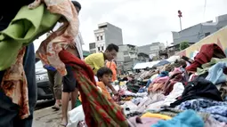 Warga korban banjir saat memilih pakaian sumbangan yang ditempatkan di pinggir Kali Ciliwung, Kampung Pulo, Jakarta Timur, Senin (6/1/2020). Banjir menyebabkan ratusan warga di Kampung Pulo kehilangan pakaian akibat rusak dan hanyut. (merdeka.com/Iqbal S. Nugroho)